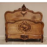 A Louis XV style walnut bed, early 20th century, of serpentine form with carved rocaille detail,