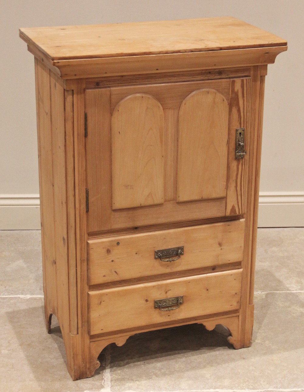 A late Victorian pine side cabinet, the single cupboard door over two drawers, flanked by inset