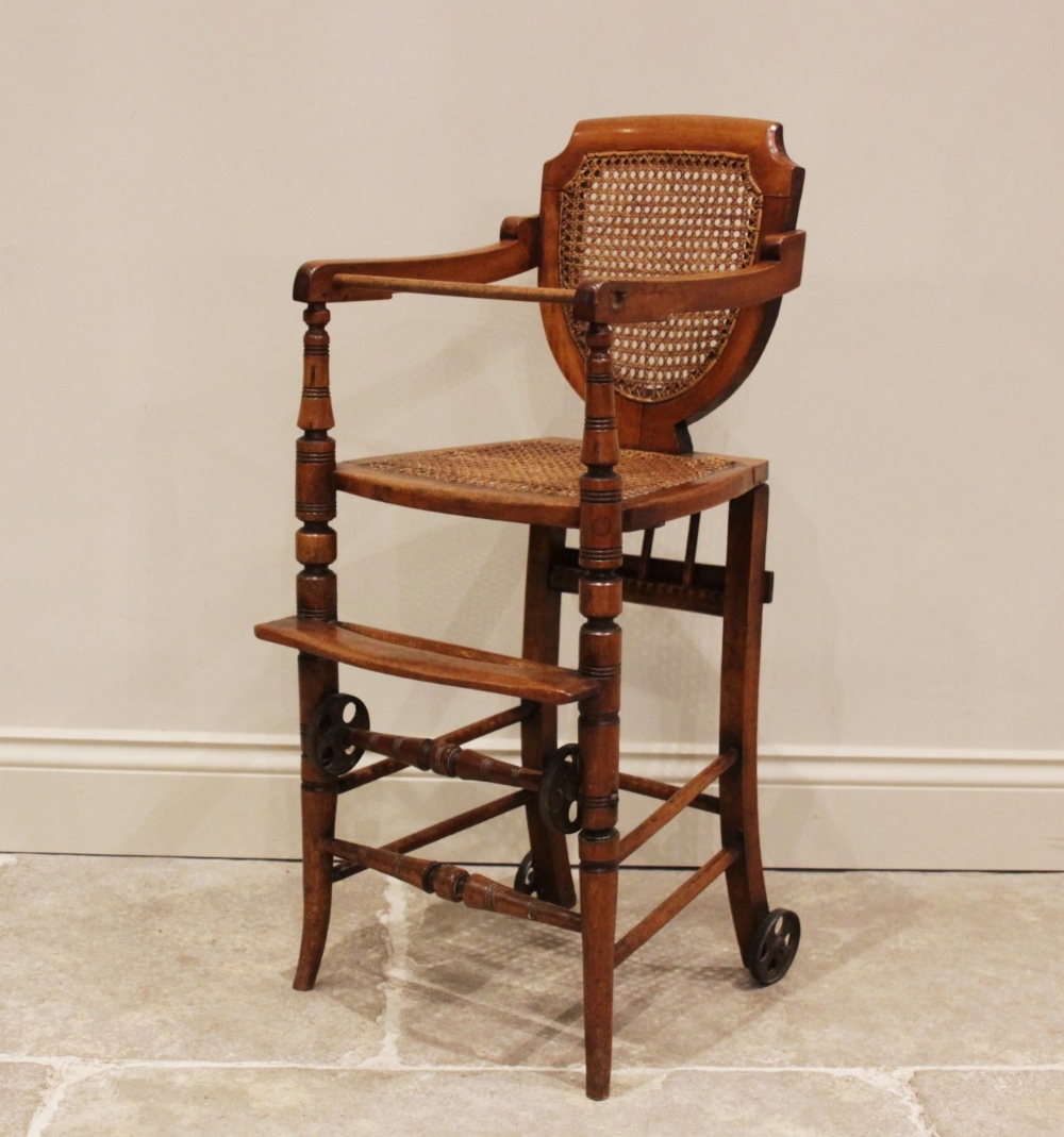 An Edwardian stained beech child's metamorphic high chair and walker with bergère shield shape