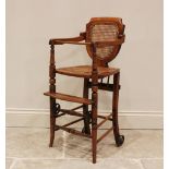 An Edwardian stained beech child's metamorphic high chair and walker with bergère shield shape
