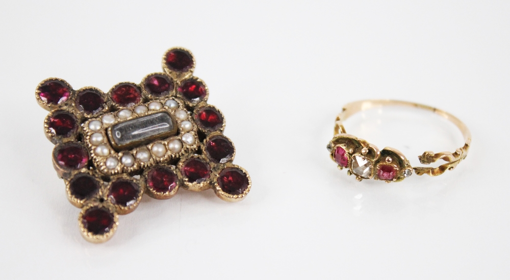 A Victorian diamond and ruby ring, designed as a central cushion cut diamond, flanked by two mixed