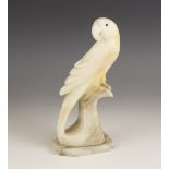 An Art Deco style carved alabaster model of a parrot, circa 1930, modelled upon a perch, 22.5cm high