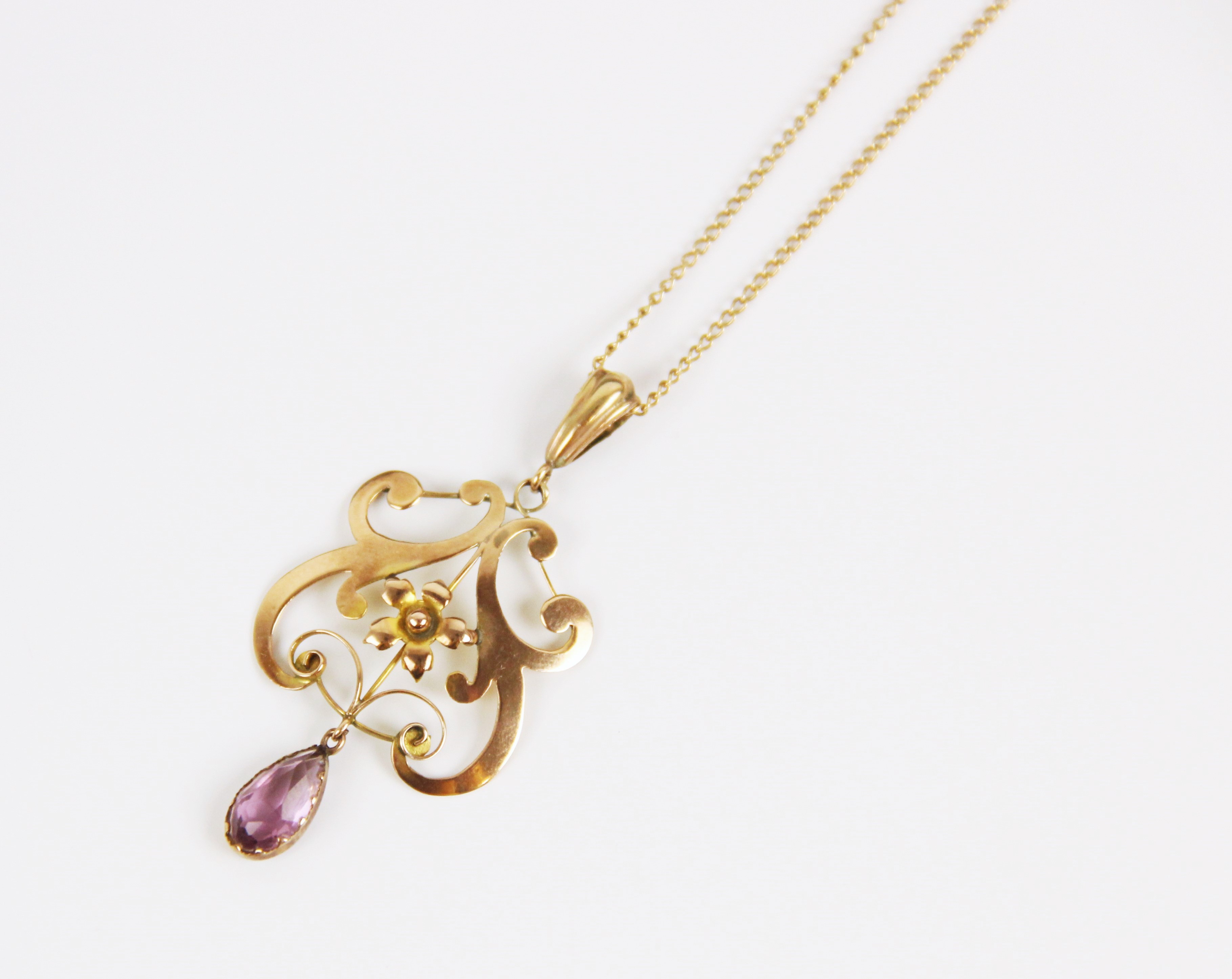 An early 20th century 9ct gold amethyst pendant, the openwork scrolling pendant with central