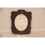 A carved oak wall mirror in the manner of Arthur Simpson, Kendal, early 20th century, the oval