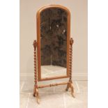 A Victorian style pine cheval mirror, late 20th century, the arched mirrored plate within a