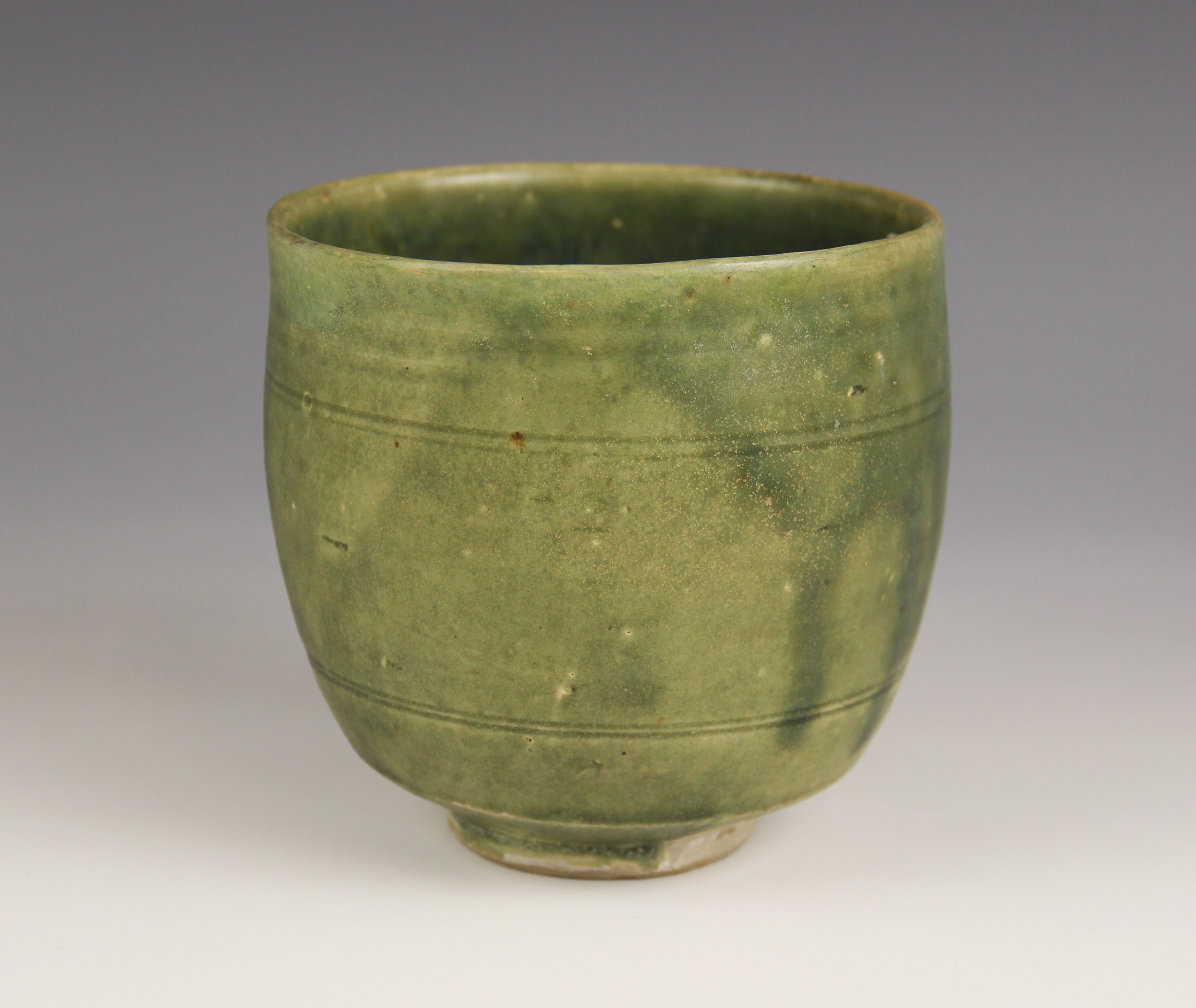 An Anamese pottery vessel, possibly 15th century, the cylindrical vase celadon glazed to the