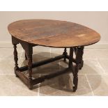 An 18th century oak drop leaf table, the oval top above a shaped frieze