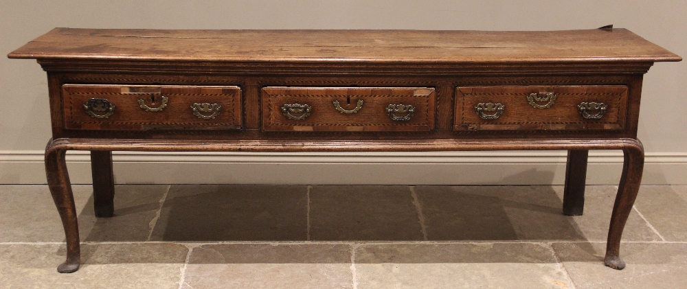 A George III oak dresser base, the rectangular moulded three plank top above three lip moulded