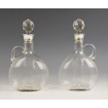 A pair of Edwardian silver collared glass decanters, each of compressed ovoid form with star-cut