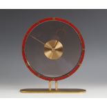 An Art Deco gilt metal and clear glass mantel timepiece, in the manner of Jaeger, the painted red