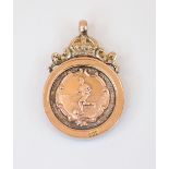 A gold coloured football fob medal, of circular form, the cartouche depicting a footballer,