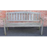 A slatted hardwood garden bench, the arched back rest above a board seat, upon legs of square