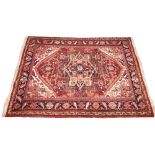 A vintage terracotta ground Persian Heriz rug, north Iran, in red, blue, green and ivory colourways,