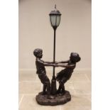 A composite bronze patina figural standard lamp, late 20th century, the lamp modelled as a street