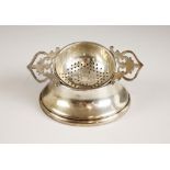 A George VI silver tea strainer and stand, the strainer with twin pierced handles, and plain