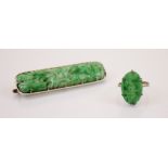 An Art Deco style jade ring, the claw set carved oval panel ring decorated as flowers, 2cm long,