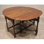 An 18th century oak drop leaf dining table, the oval top over a shaped apron upon ring turned
