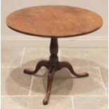 A George III oak tripod table, the circular plank top upon a baluster pedestal, three cabriole