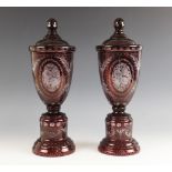 A pair of Bohemian ruby flashed glass urns and covers, each extensively wheel cut with floral and