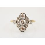 An early 20th century diamond ring, the three central graduated old cut diamonds with a surround