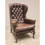 A George III style brown leather wing back armchair, mid 20th century, applied with peripheral