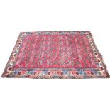 A Turkish wool carpet, in red, blue and ivory colourways, the central red field overlaid with