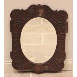A carved oak wall mirror in the manner of Arthur Simpson, Kendal, early 20th century, the oval