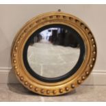 A Regency giltwood and gesso convex circular wall mirror, the moulded frame applied with sphere