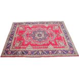 A multi coloured full pile Persian Tabriz carpet, the floral medallion upon a vibrant red ground,