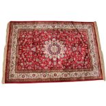 A rich red ground full pile kashmir shahbaz, with central ivory medallion extending to foliate
