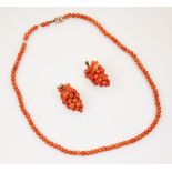 A coral bead necklace, designed as one hundred three uniform circular beads, with yellow metal