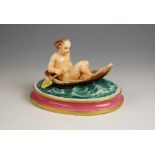 A continental porcelain figure, late 19th or early 20th century, modelled as a putti on a mussel