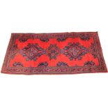 A Turkish wool rug, in red, blue and green colourways, the three central openwork medallions, upon a