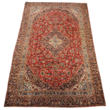 A Persian Kashan red ground wool carpet, traditional fine woven design, the central graduated