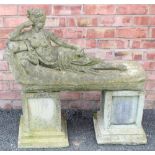 A reconstituted stone garden ornament modelled as a classical female reclining figure upon a