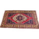 A Persian pattern wool carpet, in red, blue and ivory colourways, the central angular medallion with