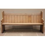 A Victorian pine pew, the shaped end supports united by a board seat,