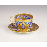 A Coalport miniature cabinet teacup and saucer, the gilt ground decorated with blue and white