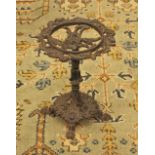 * A 19th century cast iron trivet, the scrolling foliate open work top upon a conforming cast