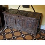 * A 17th century carved oak coffer, later converted with a hinged fall front, the three panels