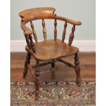 * A Victorian elm captains chair, the horseshoe top rail upon turned baluster spindles, a shaped and