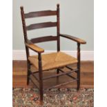 * A 19th century ladder back and rush seated elbow chair, the out swept arms upon turned supports