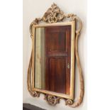 * A gilt composite wall mirror, in the rococo style, the rectangular mirrored plate within a plain