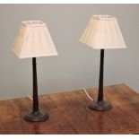 * A pair of oak column table lamps, of tapering ring turned form, extending to a moulded circular