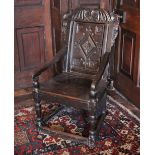 * A 16th century oak Wainscot chair, the carved foliate and scroll top rail above a panel back