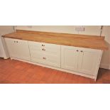 * A contemporary painted kitchen unit, the solid oak slab top over three central ‘soft close’