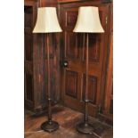 * A pair stained wood standard lamps, early 20th century, of ring turned tapering form, upon a
