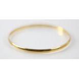 A yellow metal bangle, the plain polished bangle with indistinct stamp to interior, inner diameter