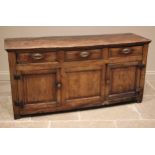 An early 18th century elm dresser base, the figured and moulded, oversailing top above an