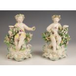 A pair of German porcelain chamber sticks, early 19th century, modelled as putti perched upon
